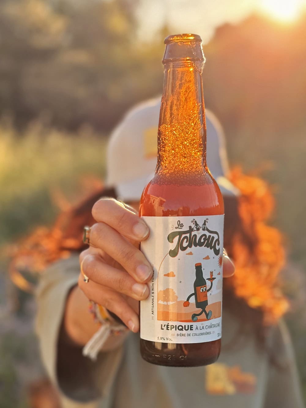 Femme tenant une bière La Tchouc durant un coucher de soleil