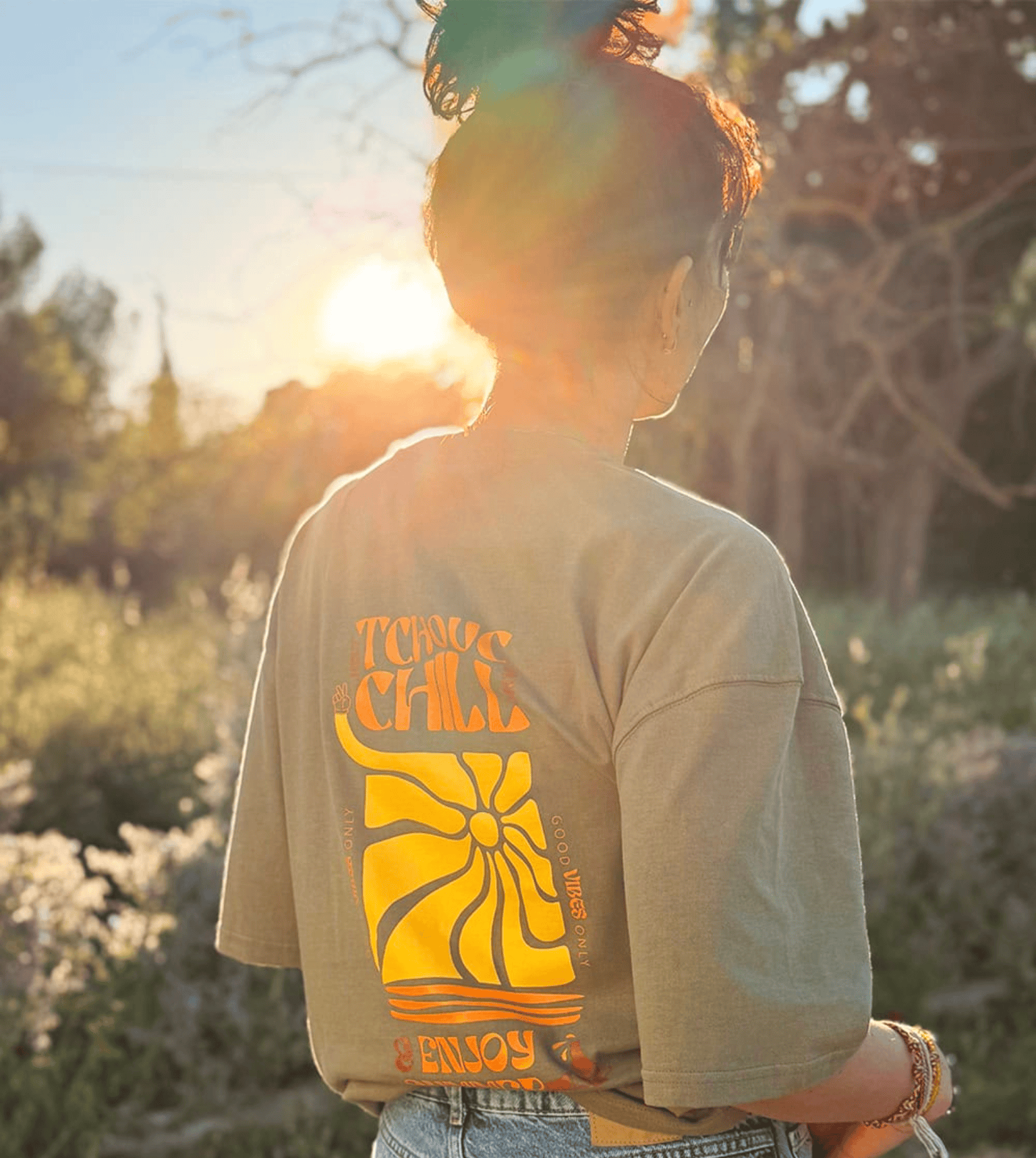 Femme face au coucher de soleil portant un tee shirt oversize de la marque Tchouc & Chill